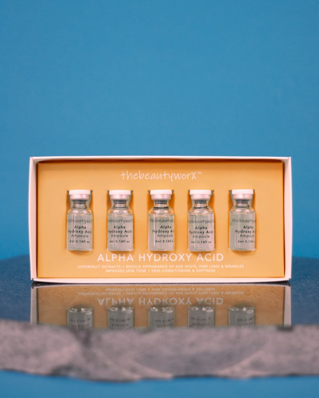 A box of thebeautyworX Alpha Hydroxy Acid ampoules on blue, reflected below