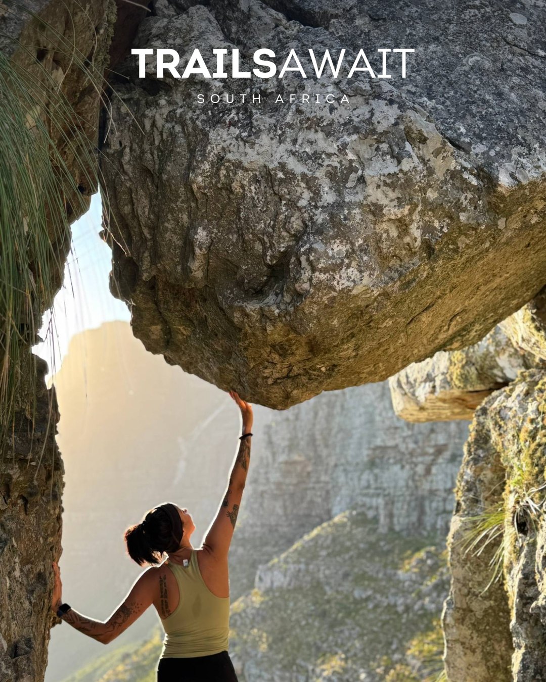 A hiker reaching up to a boulder on Table Mountain, with the Trailsawait wordmark